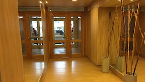 Passadís amb sòl de fusta, un mirall gran i una porta que dona a una altra habitació.