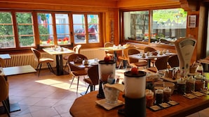 Un restaurant au décor intérieur en bois, doté de grandes fenêtres et présentant une variété de récipients contenant des aliments et des boissons sur le comptoir.