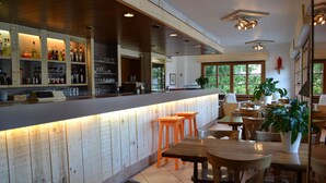 Un restaurant doté de comptoirs de bar en bois, d’espaces pour s’asseoir et de grandes fenêtres.