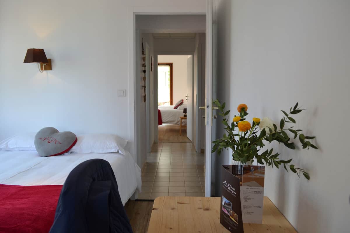 Une chambre d’hôtel avec un lit, une table de chevet, une lampe fixée au mur et un vase avec des fleurs.