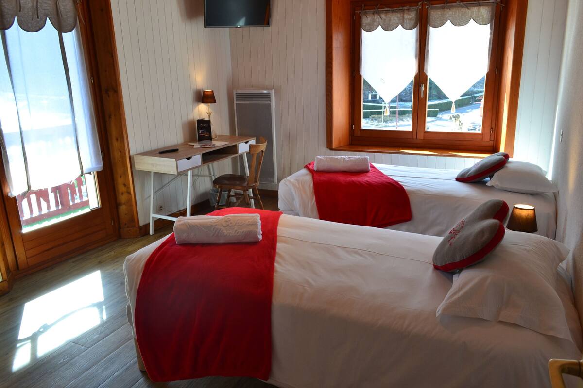 Une chambre avec deux lits, un bureau, une chaise et une télévision.