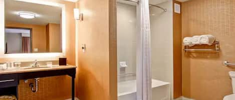 A bathroom with a sink, mirror, shower, and toilet.