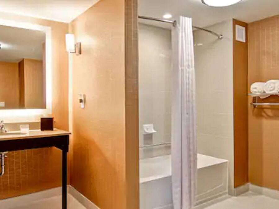 Ein Badezimmer mit Waschbecken, Spiegel, Dusche und Toilette.