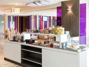 Una barra de desayuno moderna con diversos alimentos y una pared de rayas coloridas al fondo.
