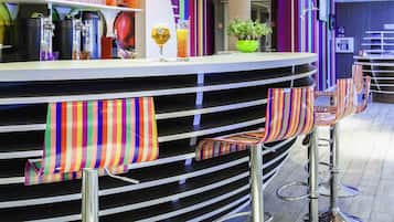 A bar area with striped barstools, a counter with various drink dispensers, and a potted plant.