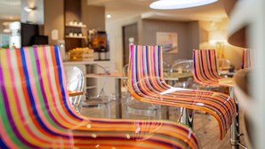 Un espace repas moderne avec des chaises rayées aux couleurs vives et un bar en arrière-plan.