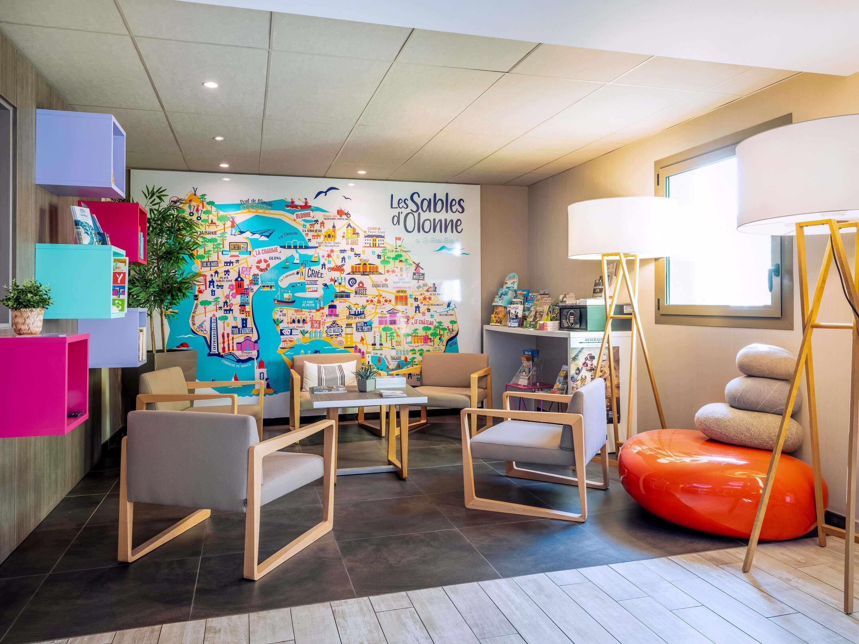 Un vestíbulo de hotel con un mural de mapa colorido, zona de estar y mostrador de recepción.