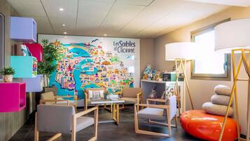 Un vestíbulo de hotel con un mural de mapa colorido, zona de estar y mostrador de recepción.
