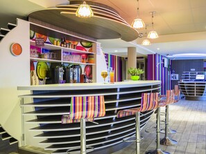 Uma área de bar com balcão, banquetas e diversos utensílios e copos.