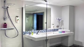 A modern bathroom with a glass shower enclosure, a white sink with a blue tile backsplash, and a hairdryer mounted on the wall.