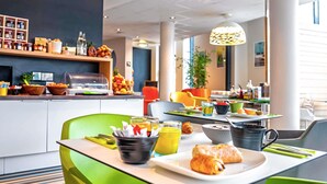 A modern breakfast area with green chairs, a buffet counter, and a variety of food and drink options. - ibis Styles Strasbourg Avenue du Rhin (Strasbourg)