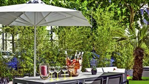 An outdoor dining area with a table, chairs, an umbrella, and a bottle of champagne. - ibis Styles Strasbourg Avenue du Rhin (Strasbourg)