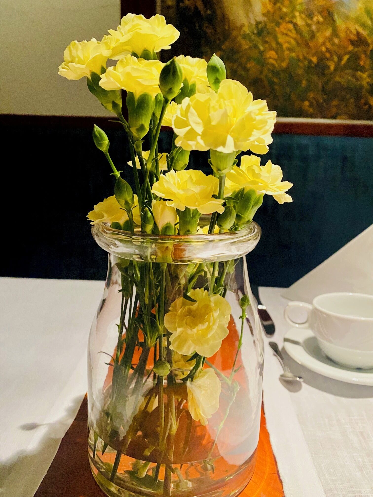 A clear glass vase with yellow flowers on a table.