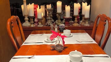 A dining table set with white tablecloth, plates, cups, and cutlery.