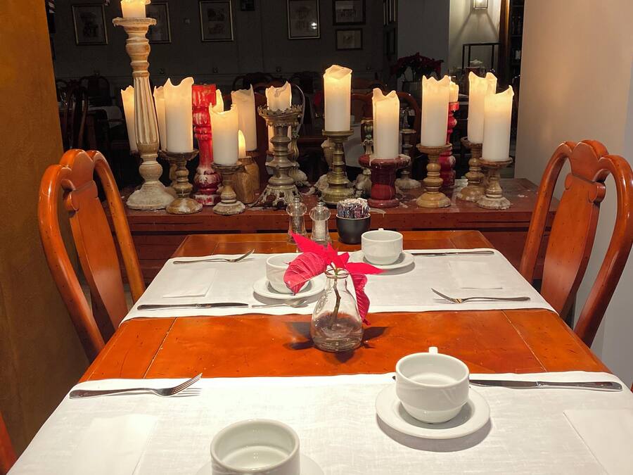 A dining table set with white tablecloth, plates, cups, and cutlery.