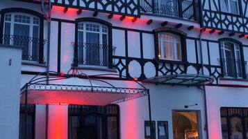 Un edificio tradicional con entramado de madera, un patio, mobiliario exterior y un camino adoquinado.