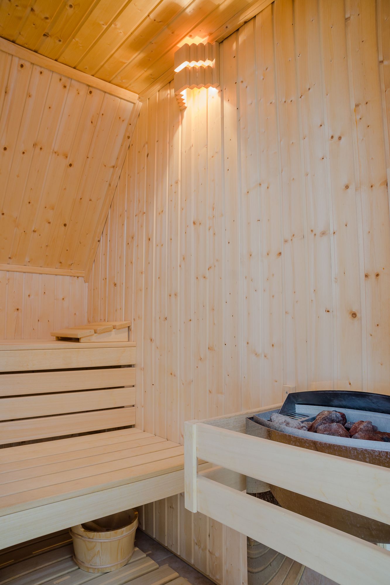 Una sauna con bancos de madera y un banco con un elemento calefactor.