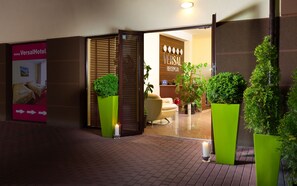 Ein Hotel-Empfangsbereich mit modernem Design, inklusive einer Rezeption, einer Sitzecke und Topfpflanzen.