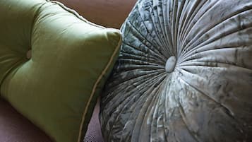 Primer plano de dos almohadas, una verde y otra gris, sobre una superficie con textura.