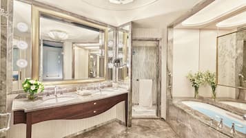 A luxurious bathroom with a large vanity, double sinks, a large mirror with lights, and a walk-in shower.
