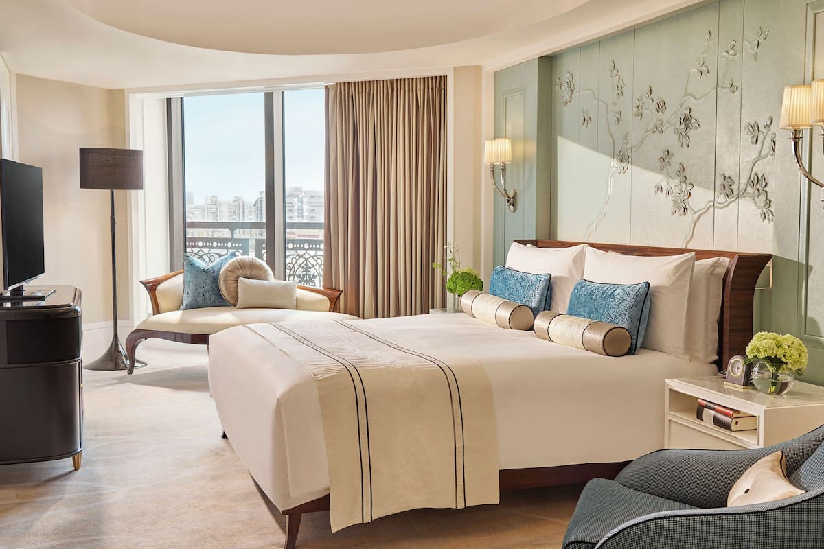 Ein Hotelzimmer mit einem großen Bett, einer Couch, einem Fernseher und Blick auf die Stadt.