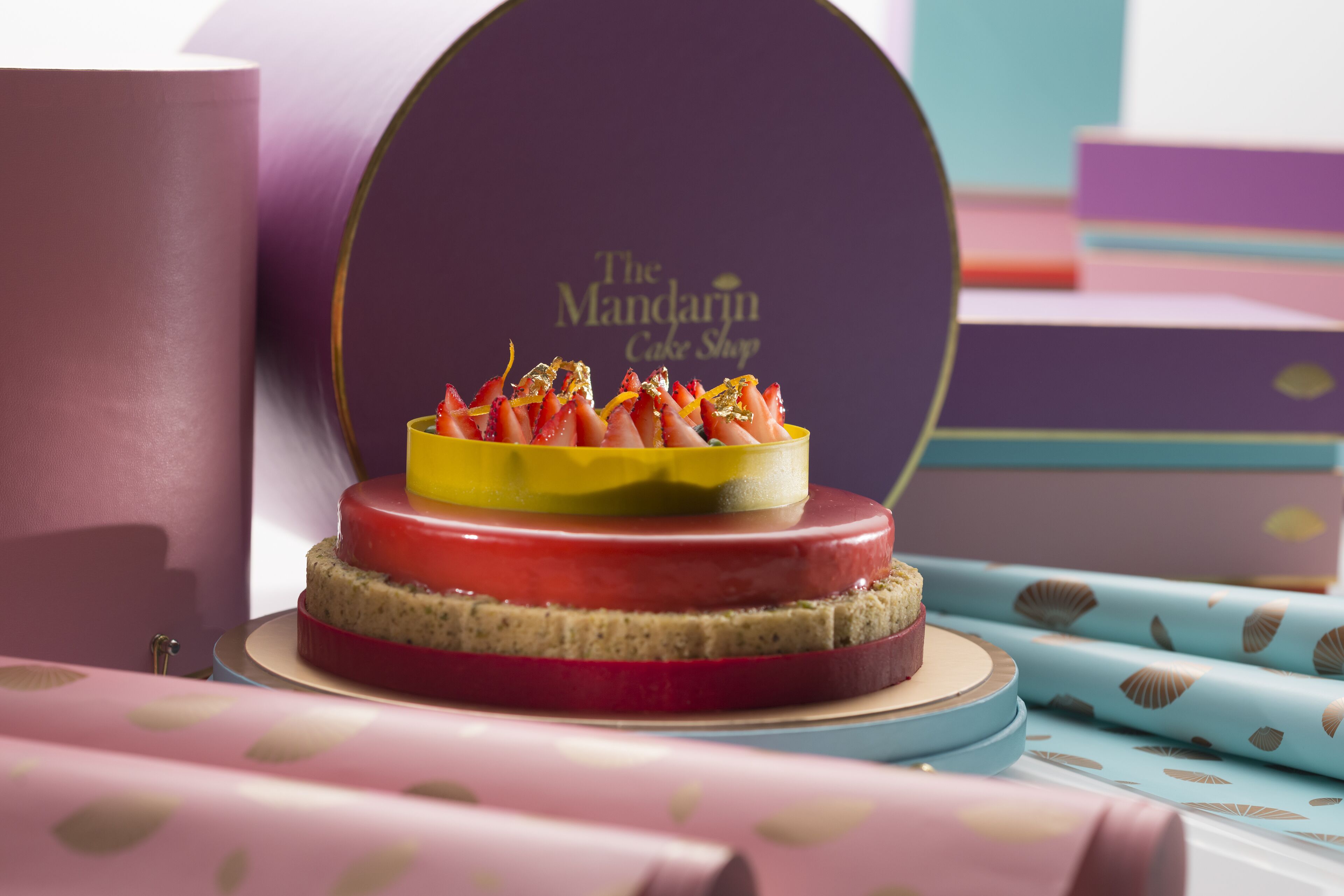 A cake with a decorative top and a box labeled "The Mandarin Cake Shop" in the background.