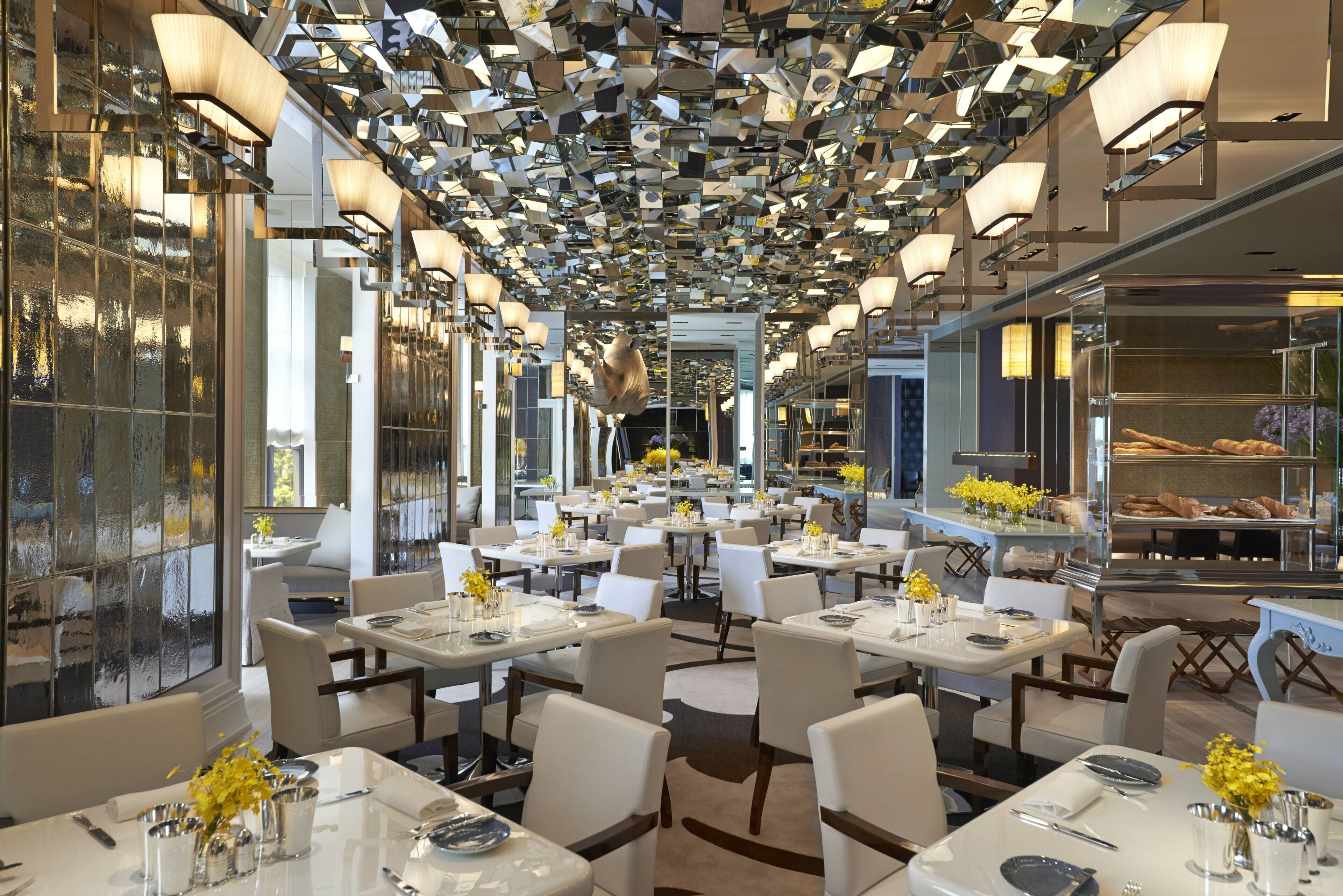 A restaurant interior with multiple dining tables, chairs, and a ceiling covered with reflective panels.