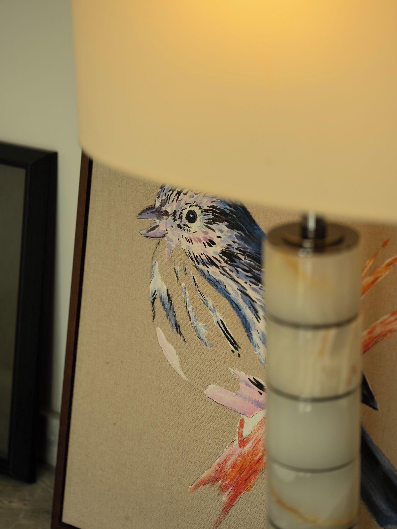 A lamp with a bird painting on its shade.