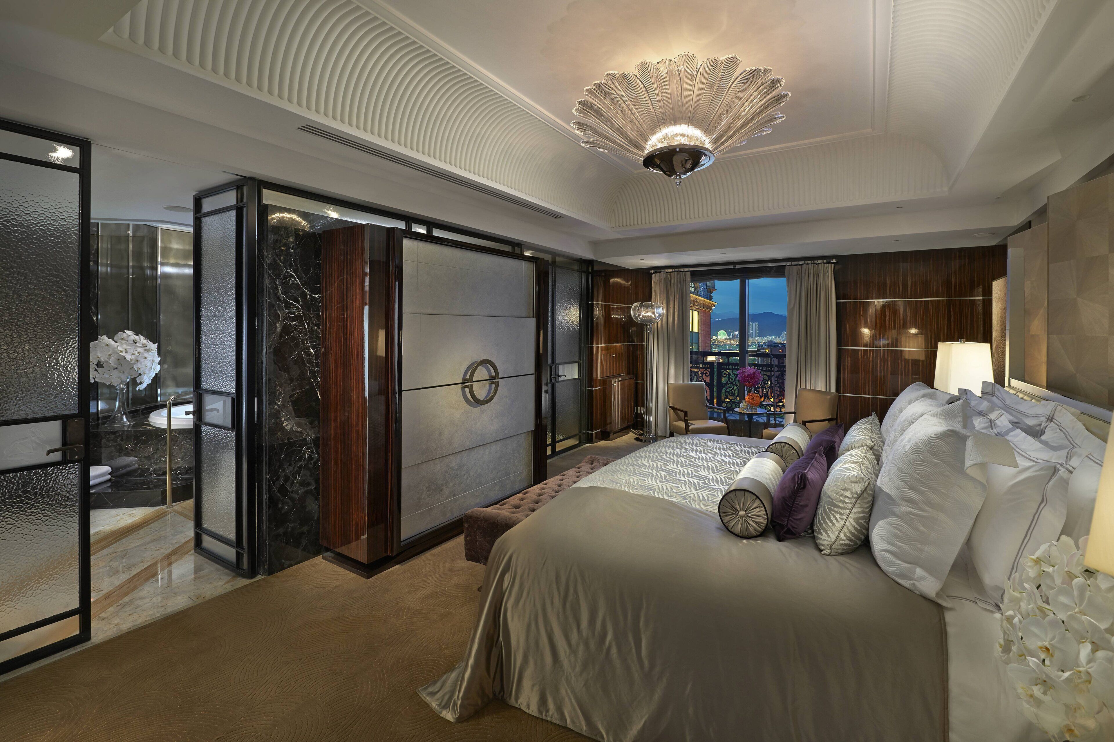 Une chambre d’hôtel moderne dotée d’un grand lit, offrant une vue sur le paysage urbain, et présentant un design de plafond unique.