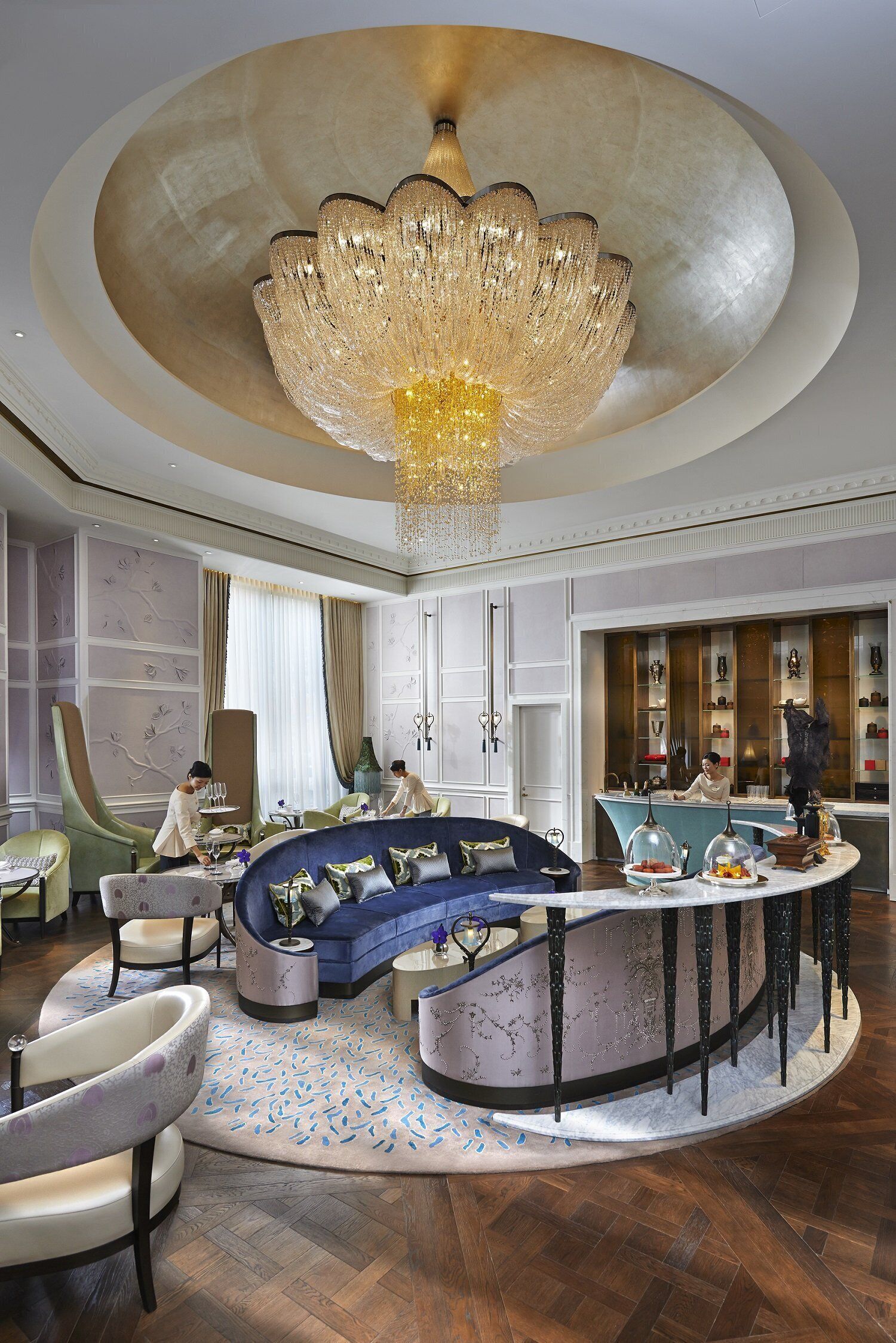 A luxurious interior with a grand chandelier, a curved seating area, and a bar.