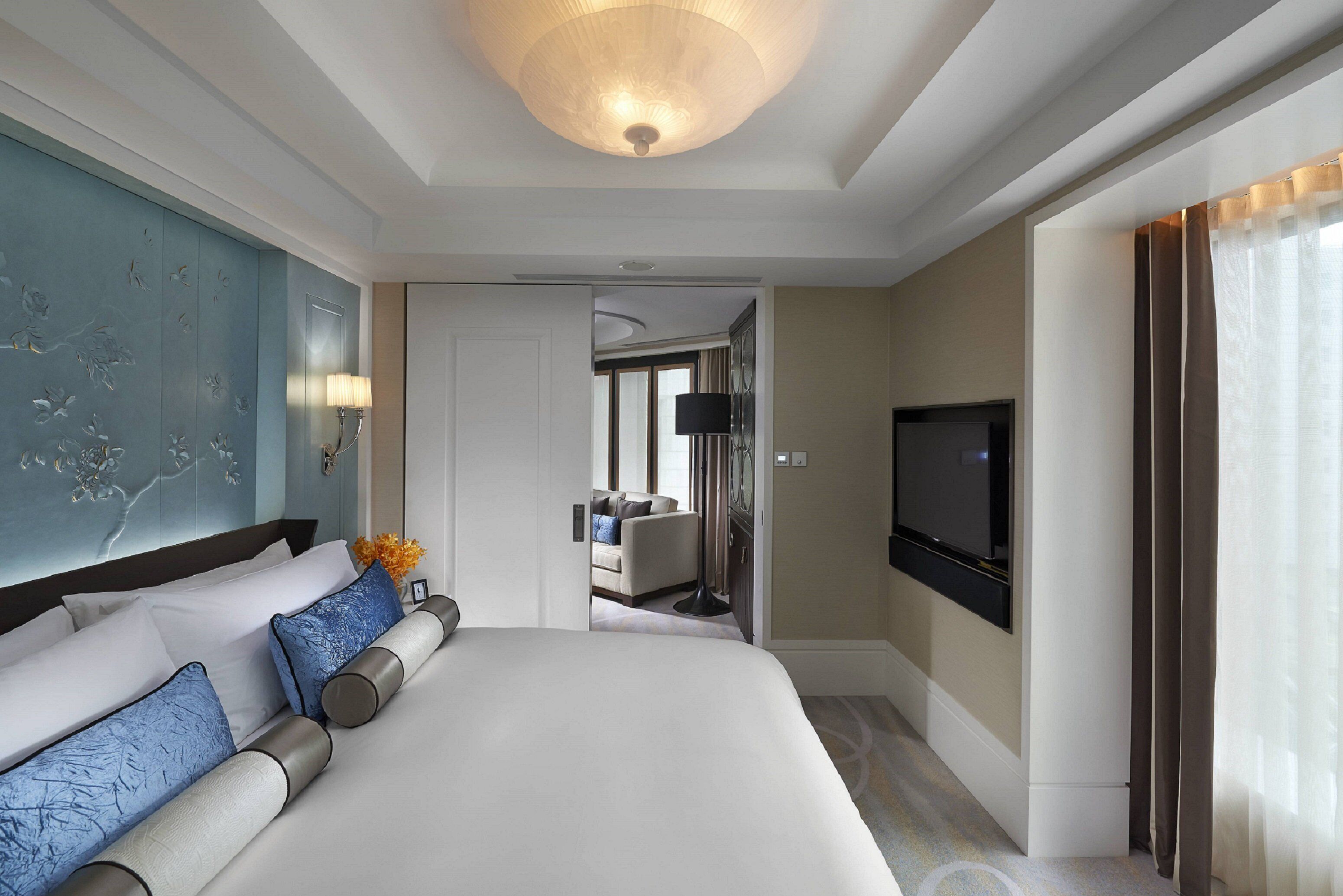 A hotel room with a large bed, a television, a mirror, and a bathroom visible through an open door.