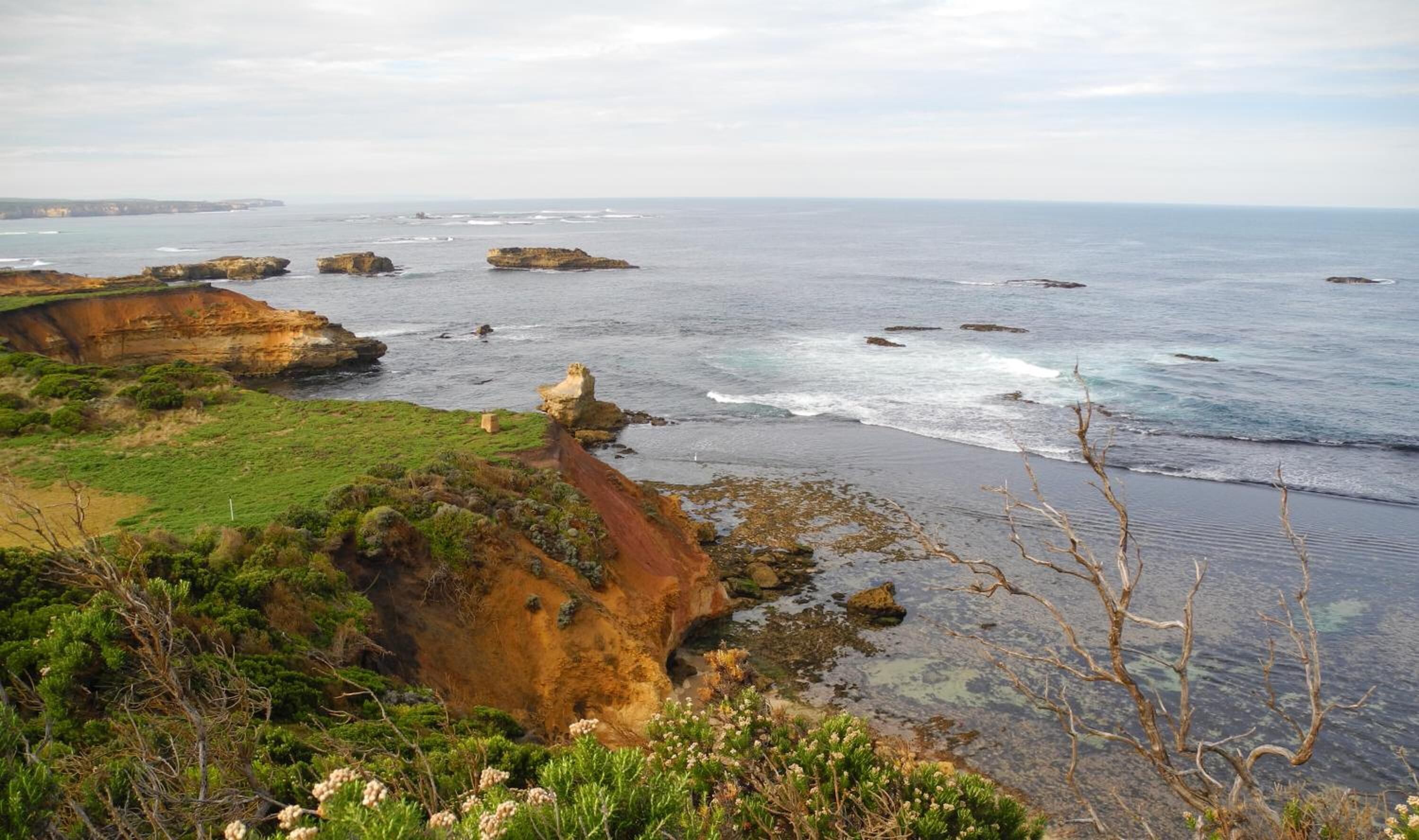 A coastal landscape with cliffs, rocky outcrops, and a beach.