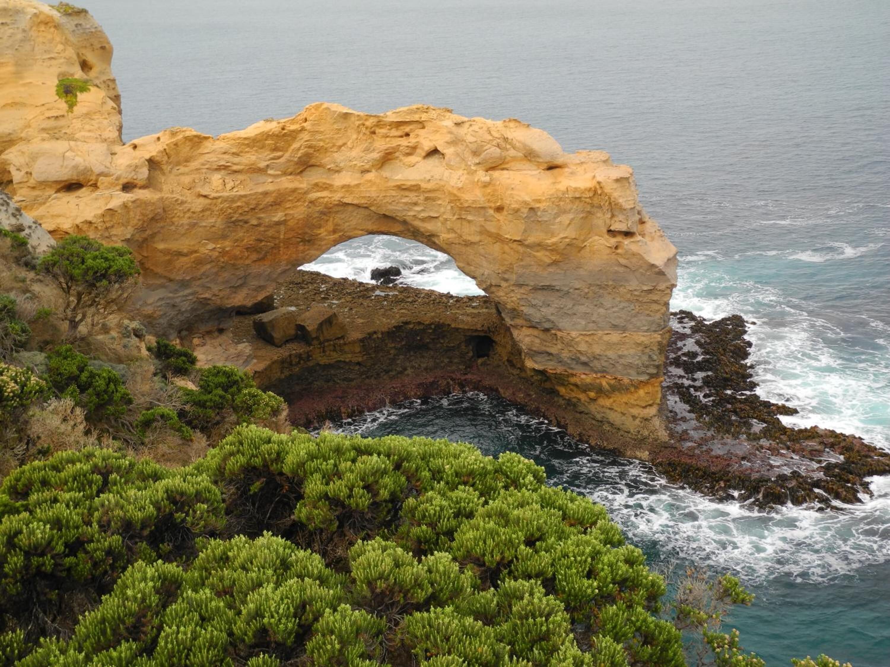 Formación natural de arco de roca con vista al mar.