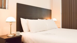 A neatly made bed with white linens, a dark headboard, and two bedside lamps. - Station Hotel Motel Kurri Kurri (Kurri Kurri)