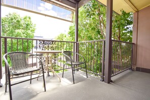 A balcony with two chairs and a small table, surrounded by a metal railing and greenery. - Station Hotel Motel Kurri Kurri (Kurri Kurri)
