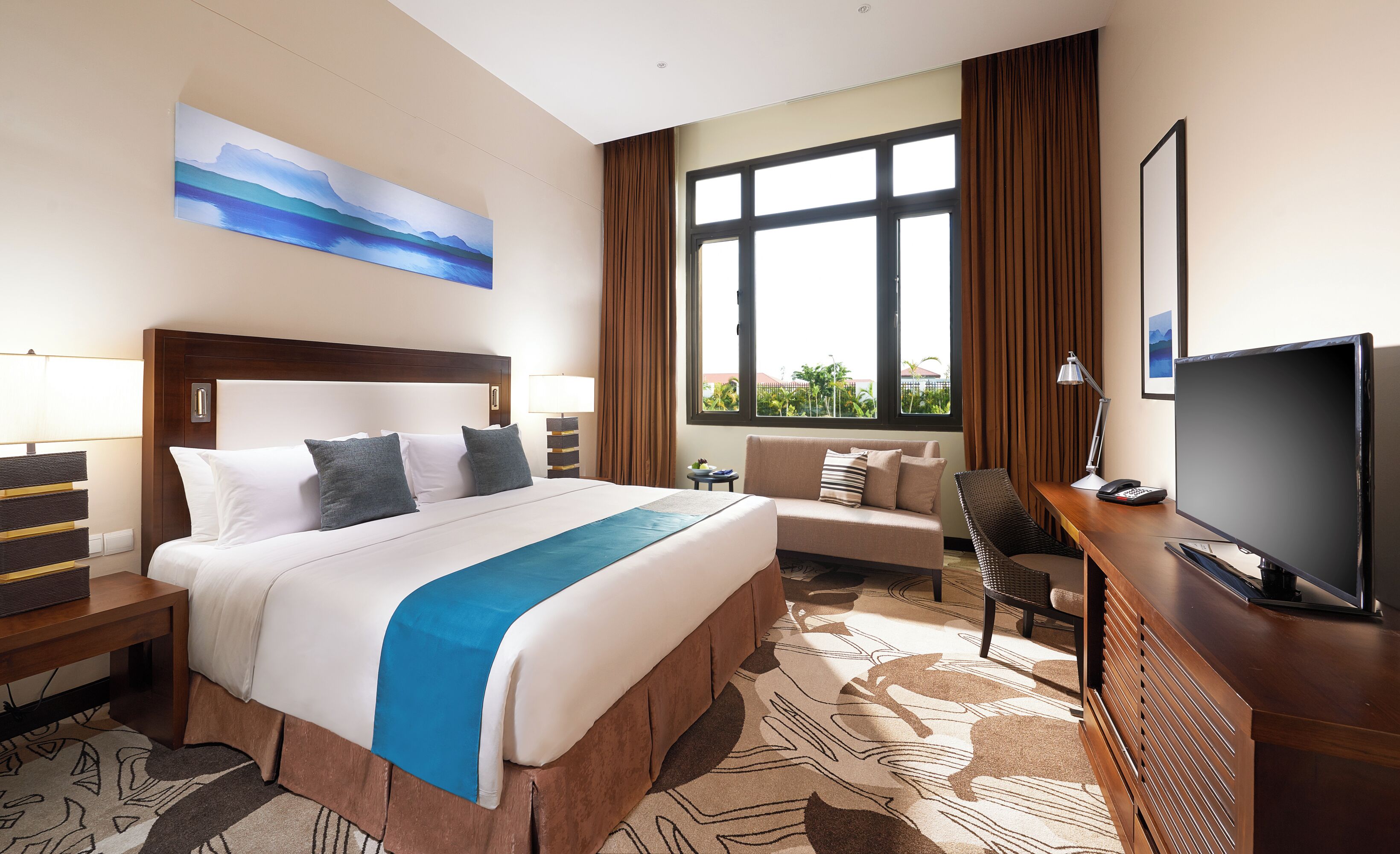 A hotel room with a bed, a sofa, a TV, and a large window.