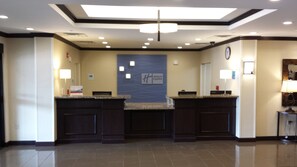 A hotel reception area with a modern design, featuring a reception desk, a clock, and a sign for the Holiday Inn Express. - Holiday Inn Express & Suites Cambridge by IHG (Cambridge)