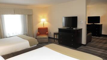 Habitación de hotel con dos camas, un escritorio, un televisor, una silla y una lámpara.
