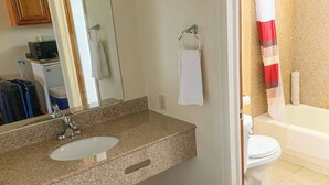 A bathroom with a granite countertop sink, a mirror, a towel rack, a toilet, and a shower curtain. - Relax Inn Bloomsburg (Bloomsburg)