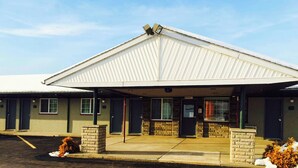 A motel with a covered parking area, multiple rooms, and a brick entrance. - Relax Inn Bloomsburg (Bloomsburg)