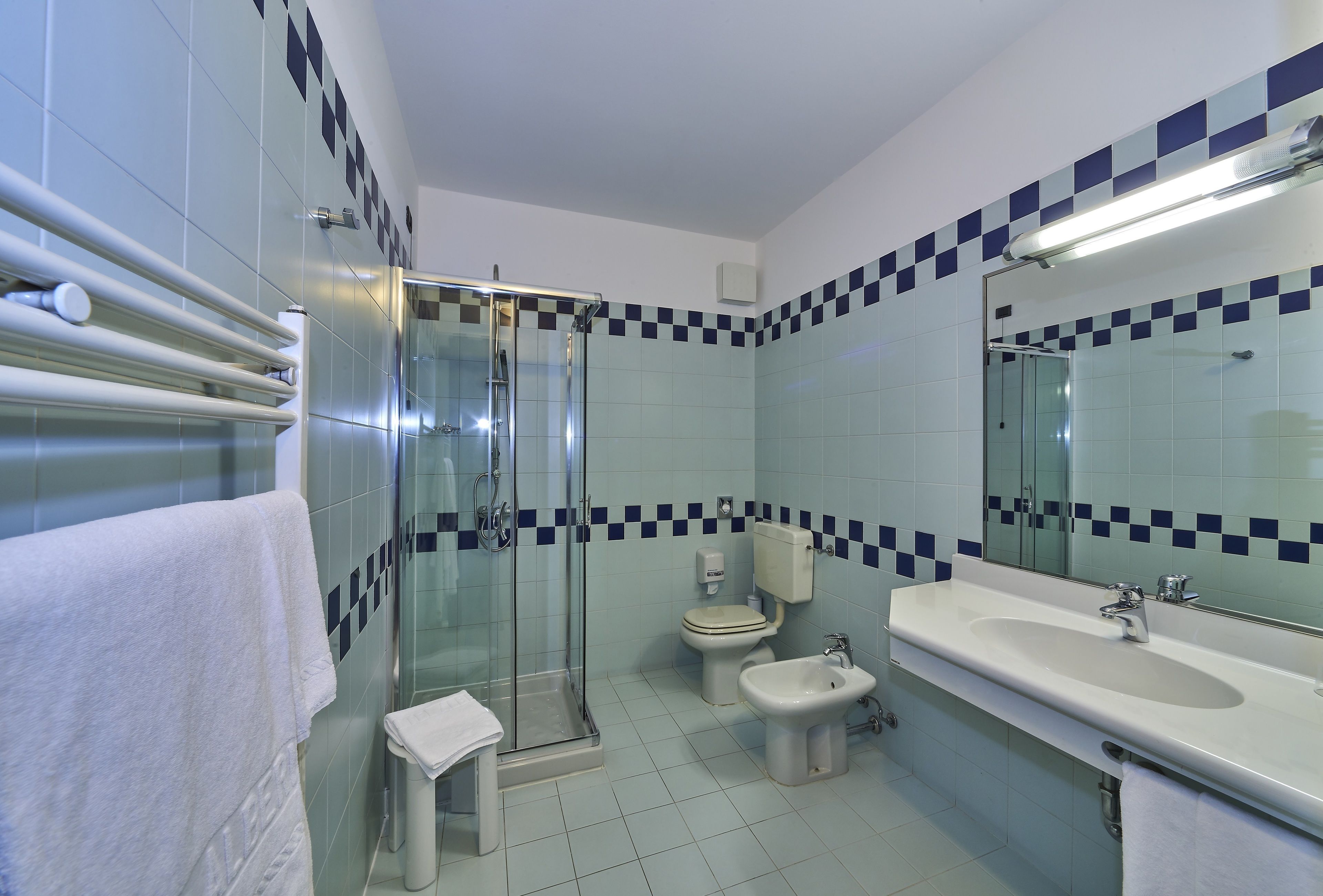 Un baño con cabina de ducha de vidrio, inodoro, bidé y lavabo con espejo.