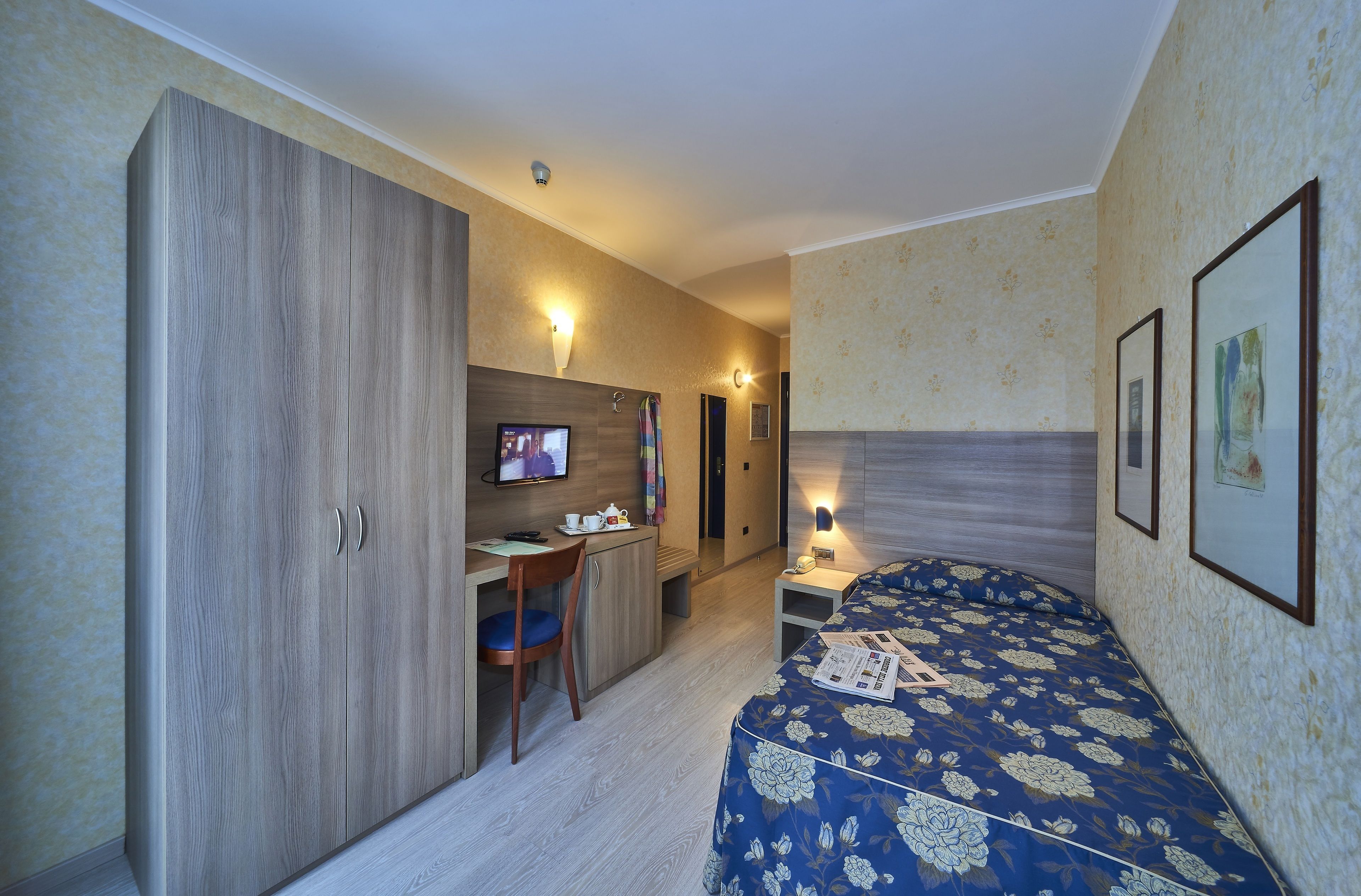 Una habitación de hotel compacta con cama, escritorio y armario.