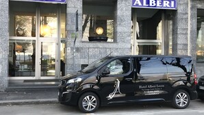 Una camioneta negra estacionada frente al Hotel Alberi Lecco, con un cartel que indica que es un hotel.