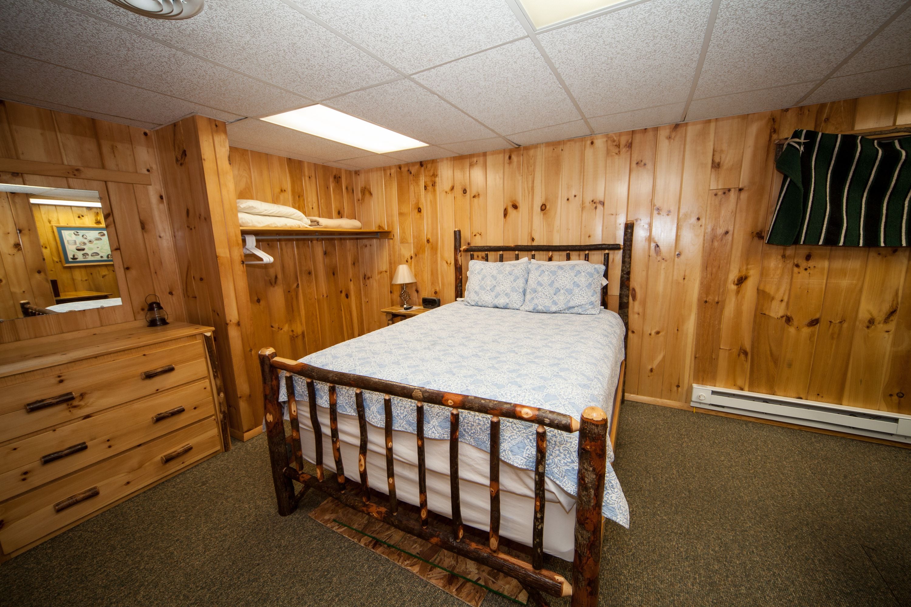 Een kamer met houten lambrisering, een bed, een dressoir en een handdoek.