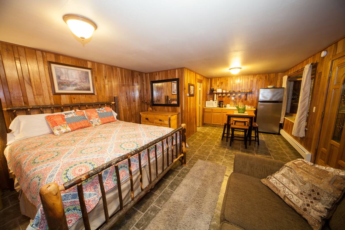 A cozy bedroom with a large bed, a wooden headboard, and a nightstand.