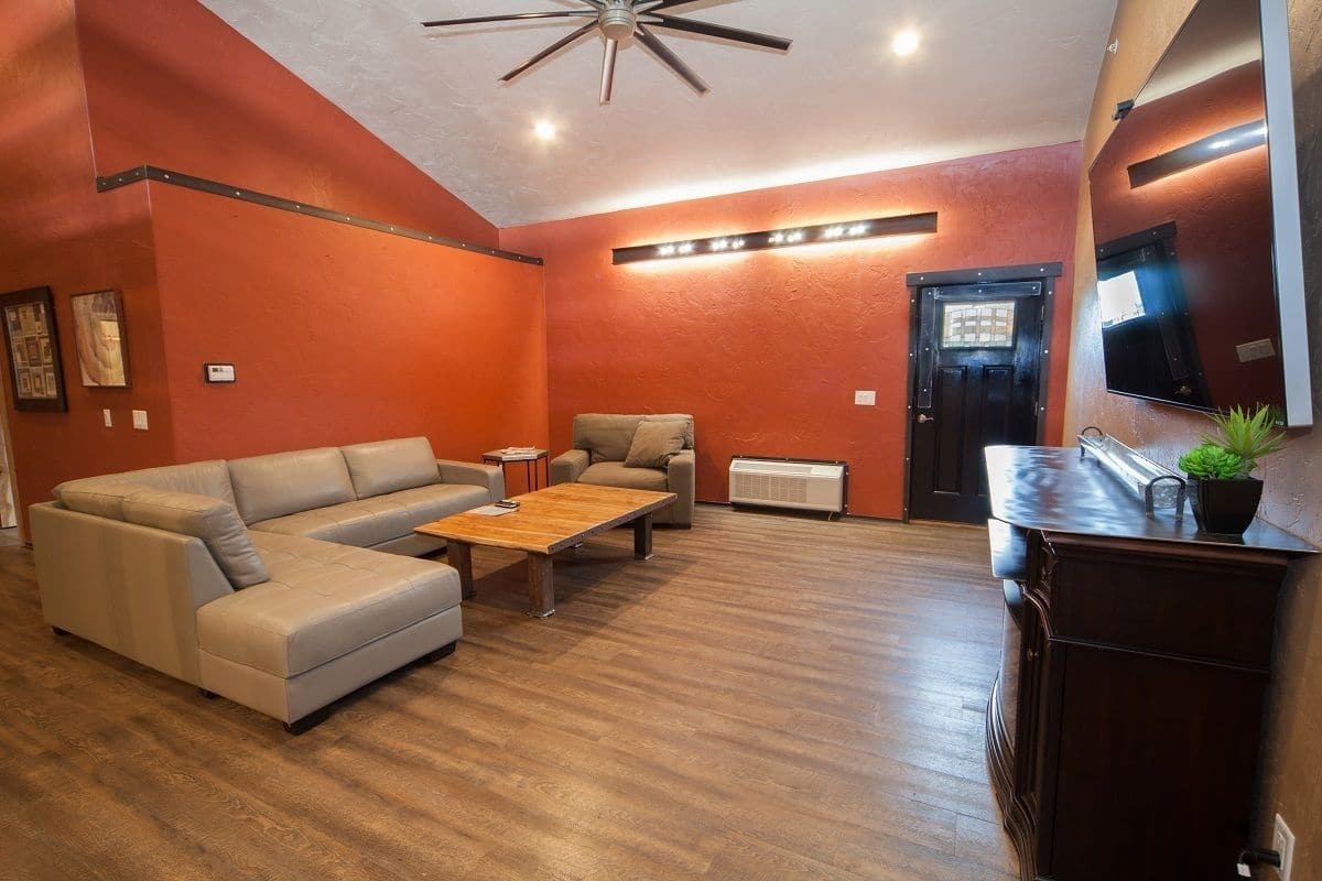 A living room with a sectional sofa, a coffee table, a TV, and a dark wooden cabinet.