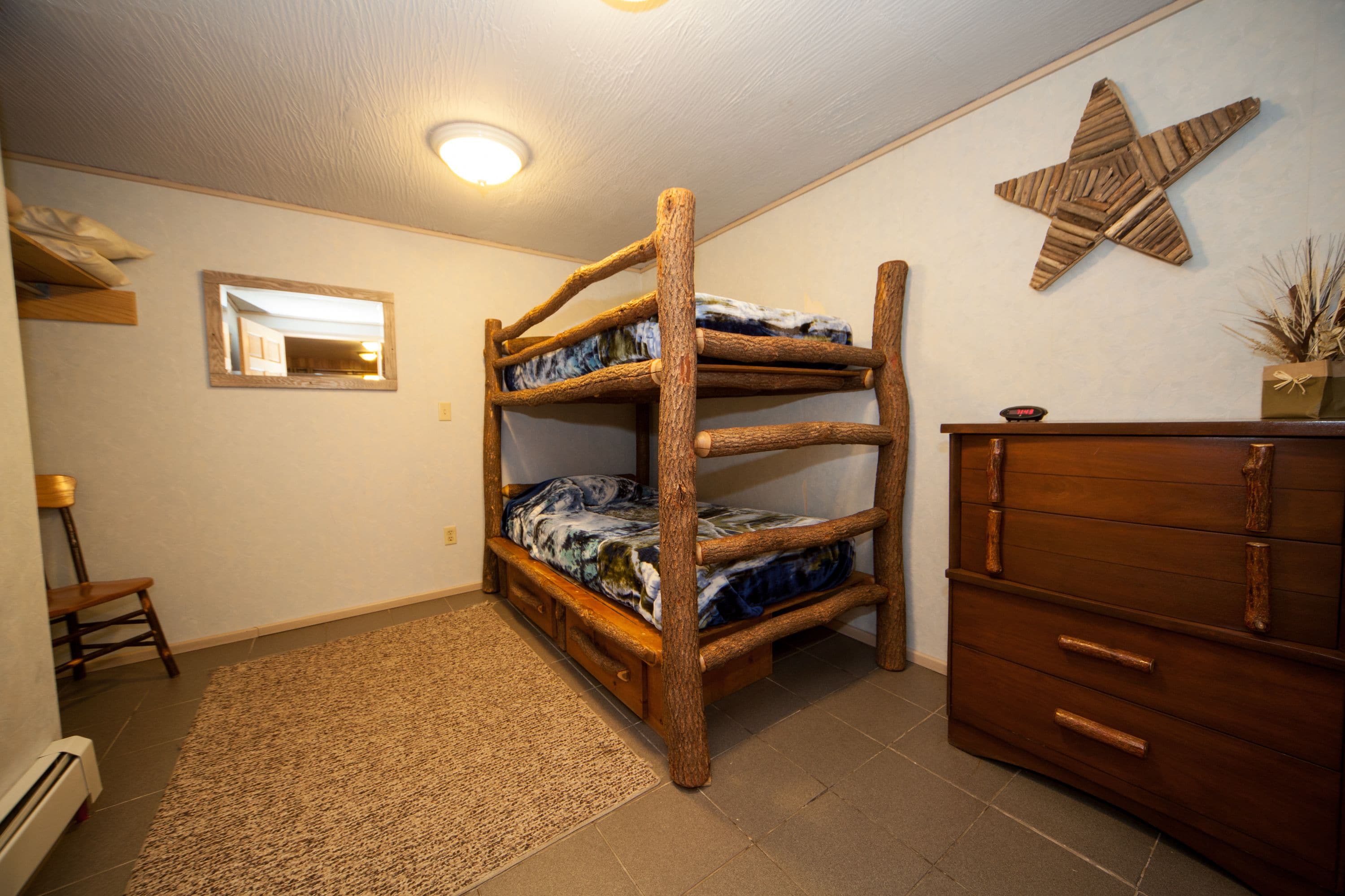 Un llit superposat amb un mirall, una commode i una decoració de estrella a la paret.