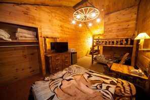 Una habitación acogedora tipo cabaña de madera con una cama, un televisor, un escritorio y una silla.
