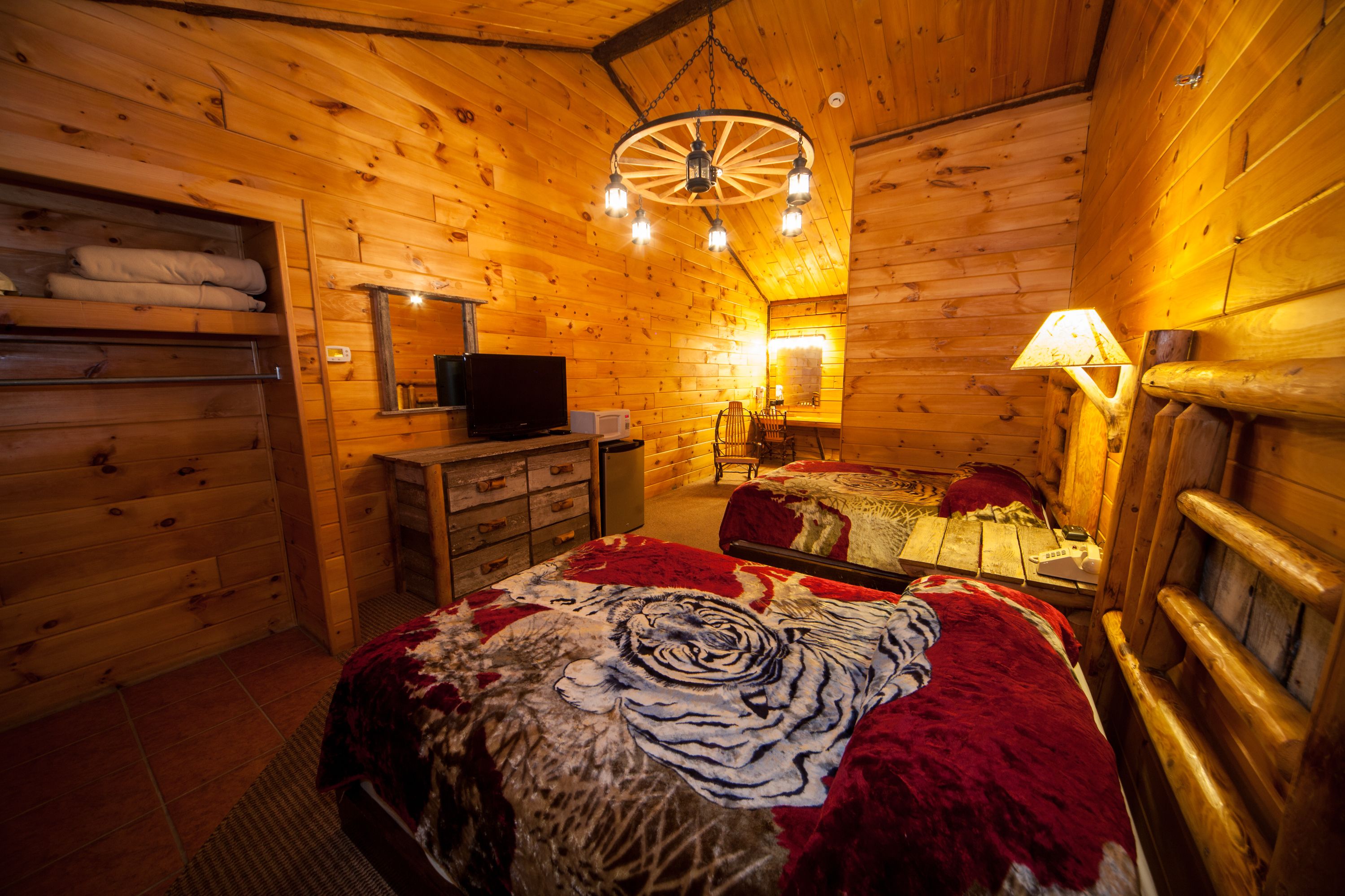 Un dormitorio rústico tipo cabaña de madera con cama, cómoda y televisor.