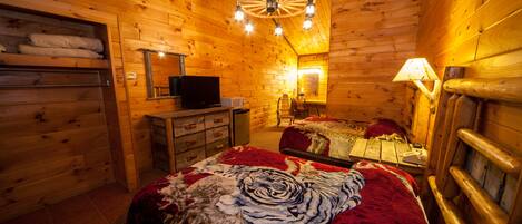Un dormitorio rústico tipo cabaña de madera con cama, cómoda y televisor.